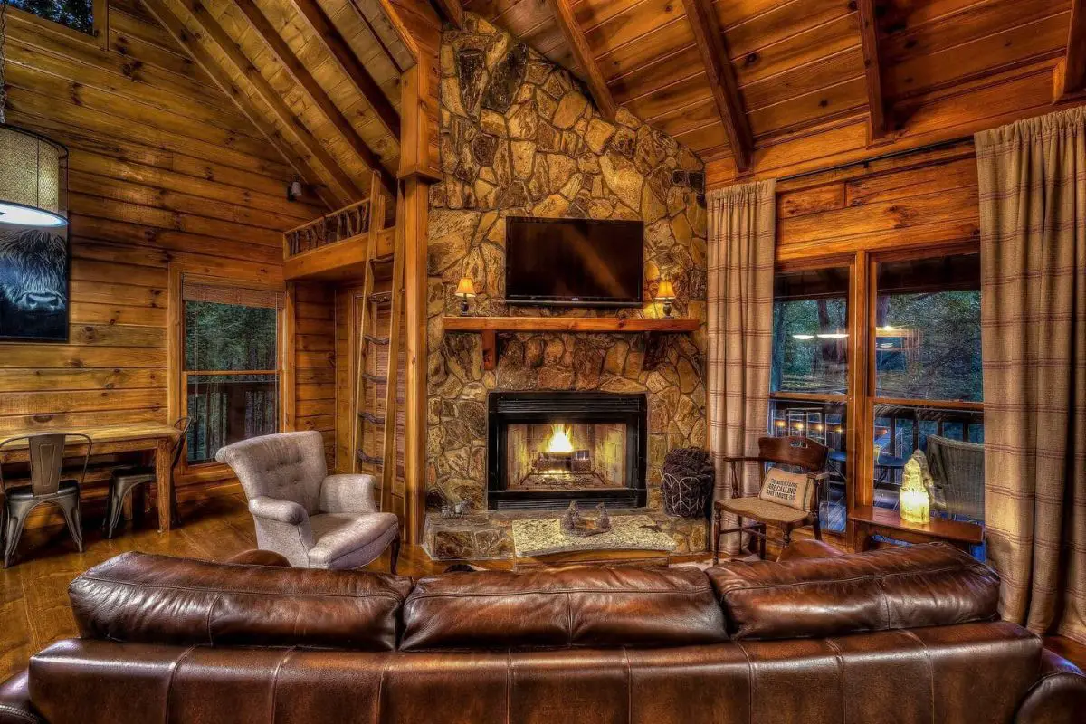 stone fireplace between windows in cabin living room